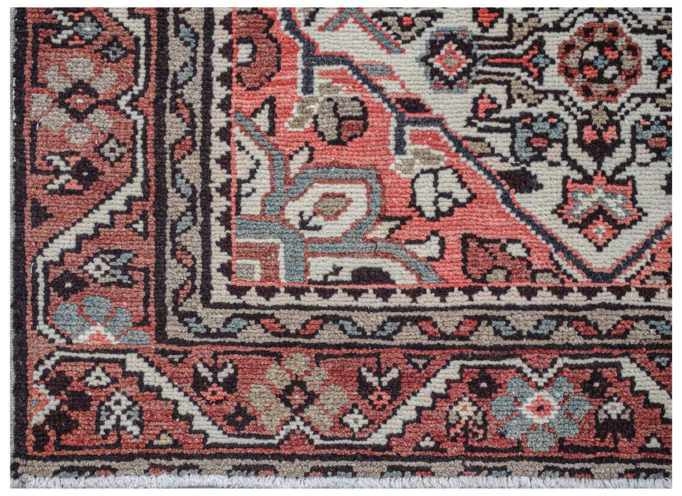 A close-up of a vintage handwoven Persian rug featuring intricate floral patterns in red and blue.