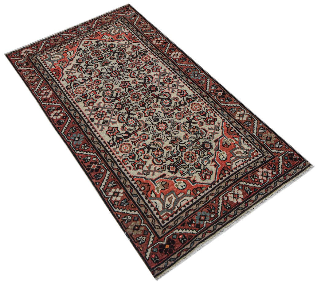 Vintage Persian rug with intricate floral patterns in red, cream, and black.