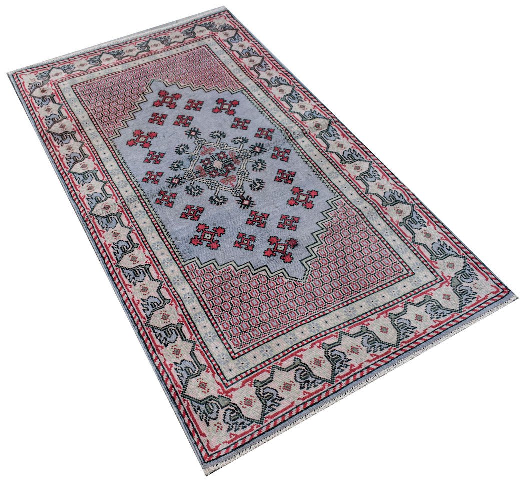 A handwoven vintage Persian rug featuring a blue central medallion with red geometric patterns.