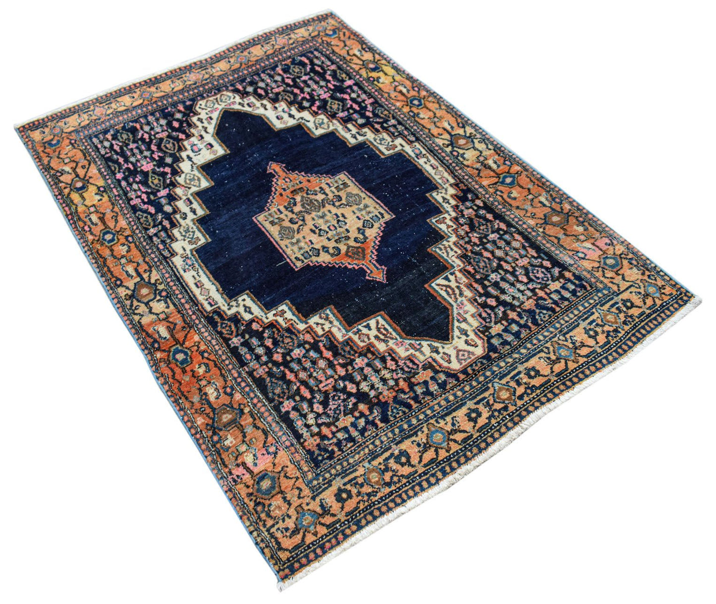 A handwoven vintage Persian rug featuring a dark blue central medallion and orange floral borders.