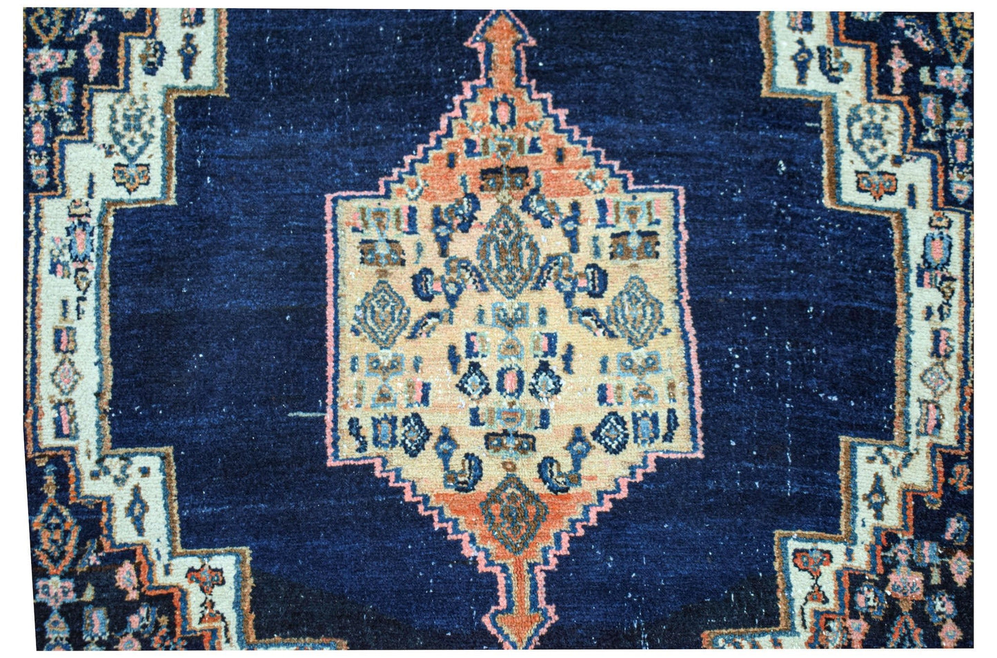 A vintage handwoven Persian rug featuring a central geometric medallion on a deep blue field.