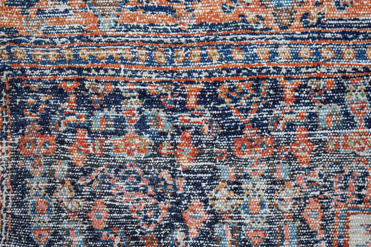 A vintage Persian rug featuring a detailed floral pattern in shades of blue, orange, and cream.