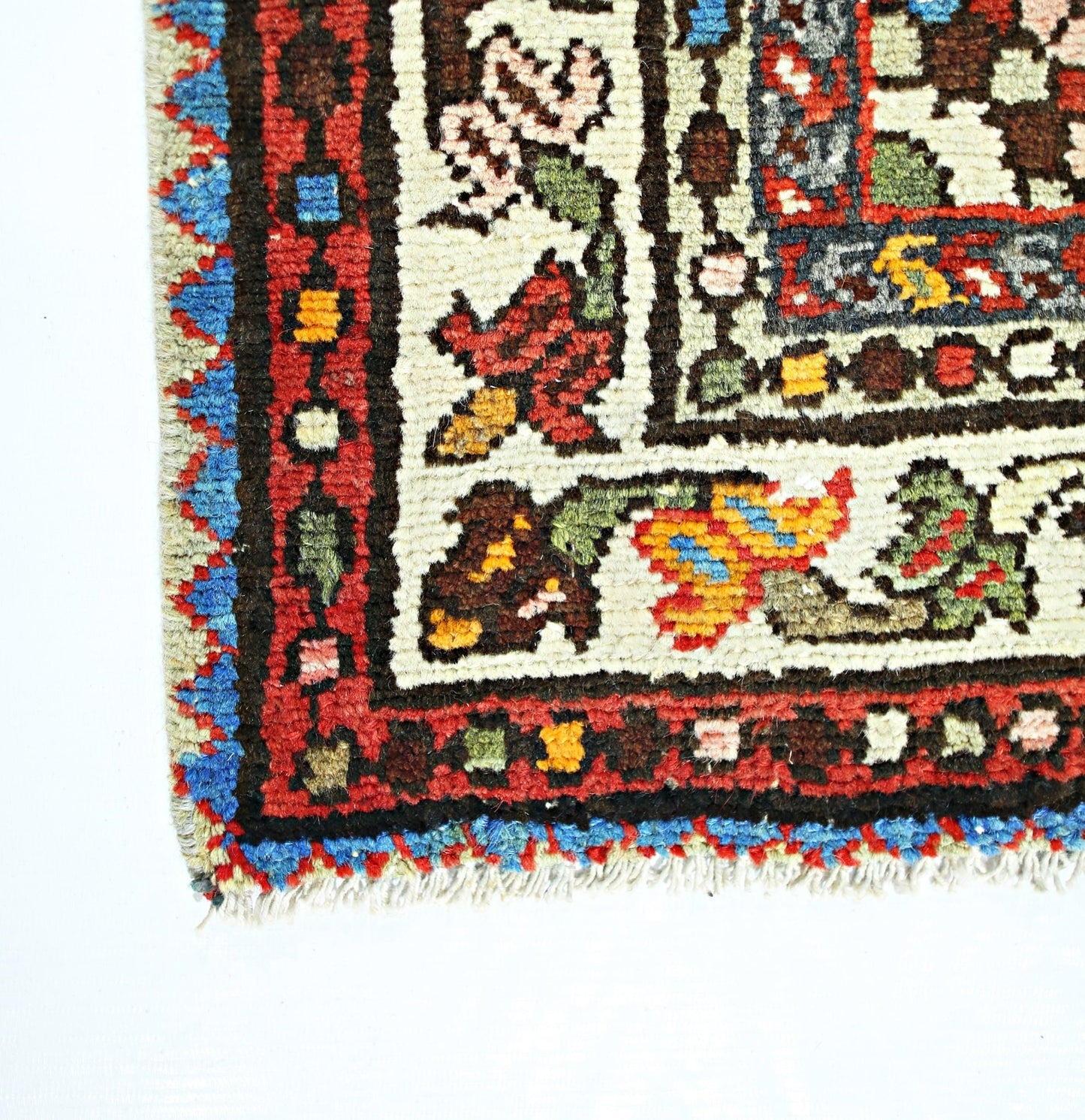 A corner view of a vintage Persian Sarouk rug featuring intricate floral patterns and wool pile.