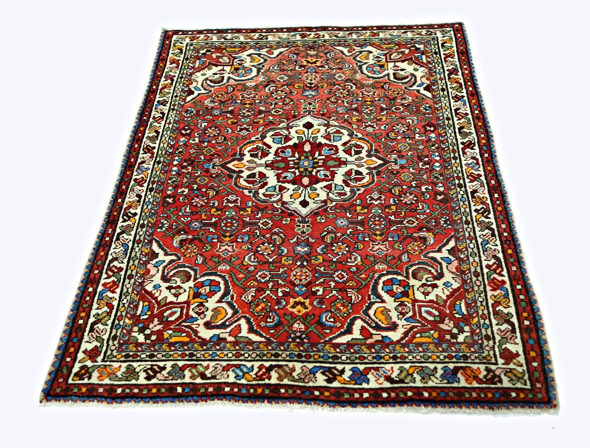 A vintage Persian Sarouk rug featuring a central floral medallion on a vibrant red field.