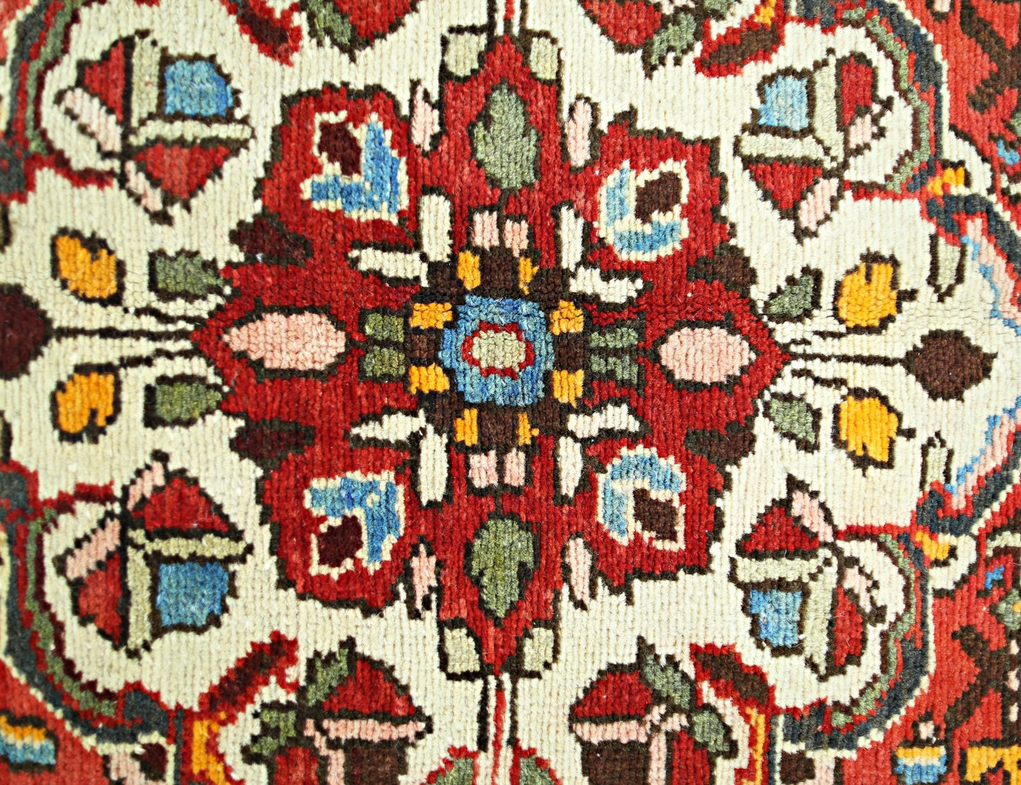 A close-up of a vintage Persian Sarouk rug featuring a vibrant floral medallion pattern.