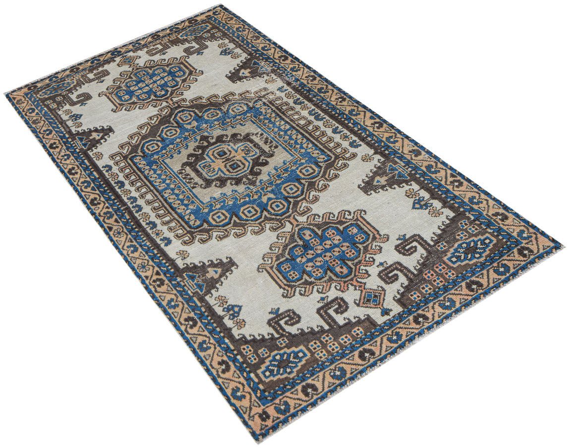 A handwoven vintage Persian rug featuring a geometric pattern in shades of blue, brown, and cream.