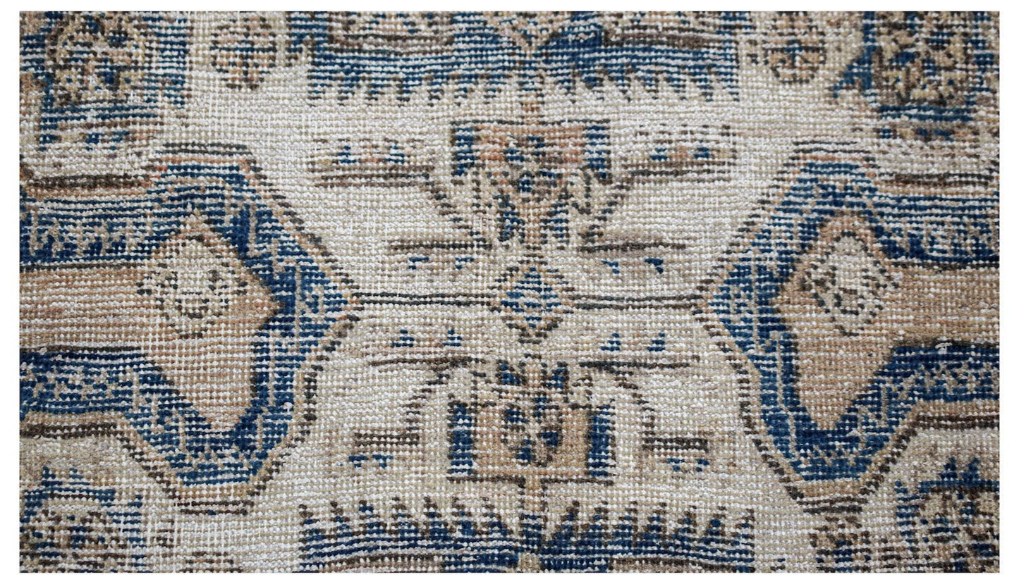 A vintage handwoven Persian rug featuring a geometric pattern in shades of blue and beige.