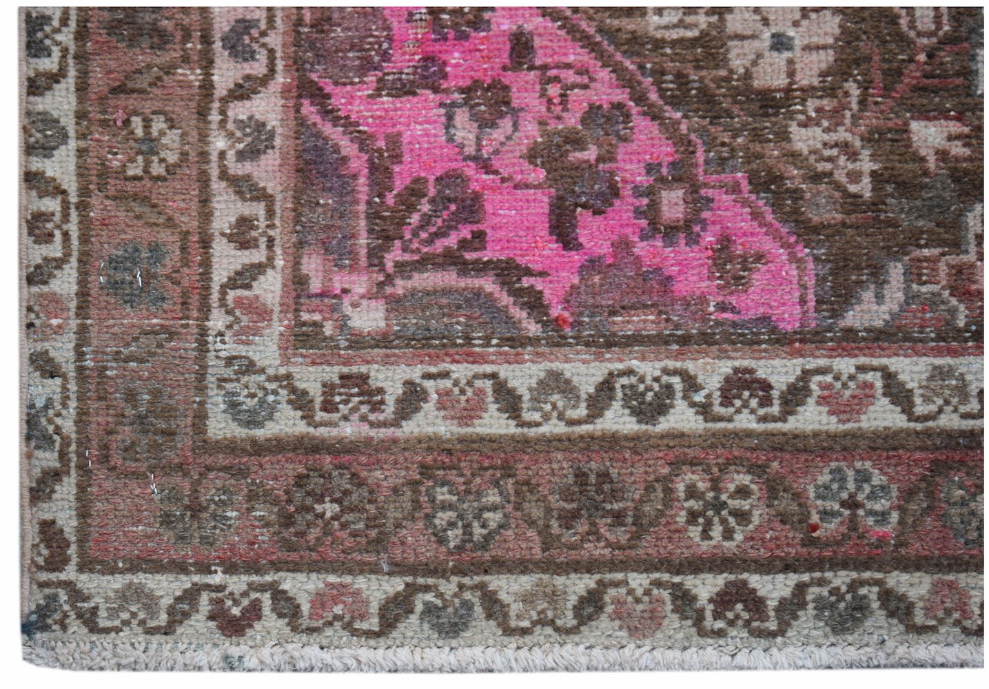 A vintage handwoven Persian rug featuring a vibrant pink and brown floral pattern.