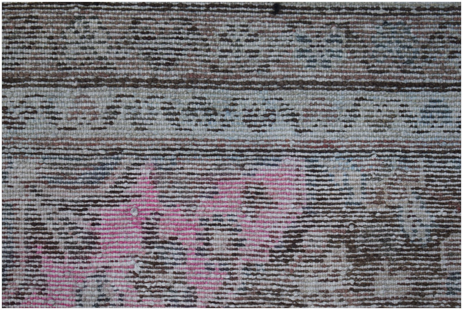 A vintage handwoven Persian rug featuring a distressed pattern in shades of pink, brown, and cream.