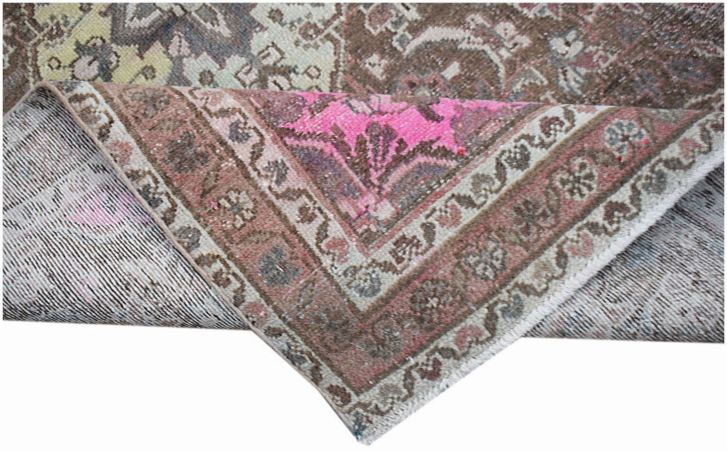 A vintage handwoven Persian rug with a distressed floral pattern in shades of pink and brown.