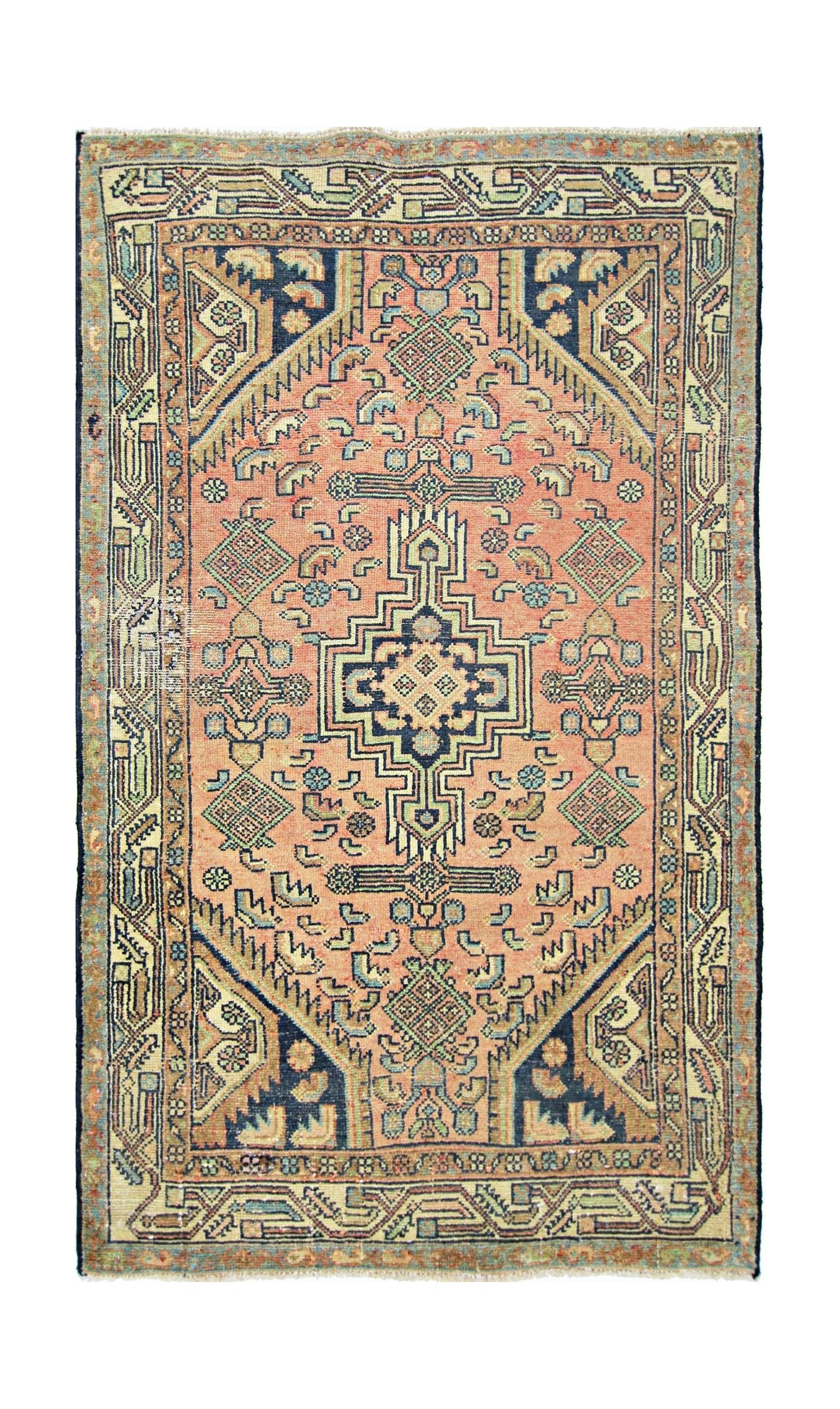 A vintage handmade Persian rug featuring a geometric medallion pattern in salmon and navy blue.