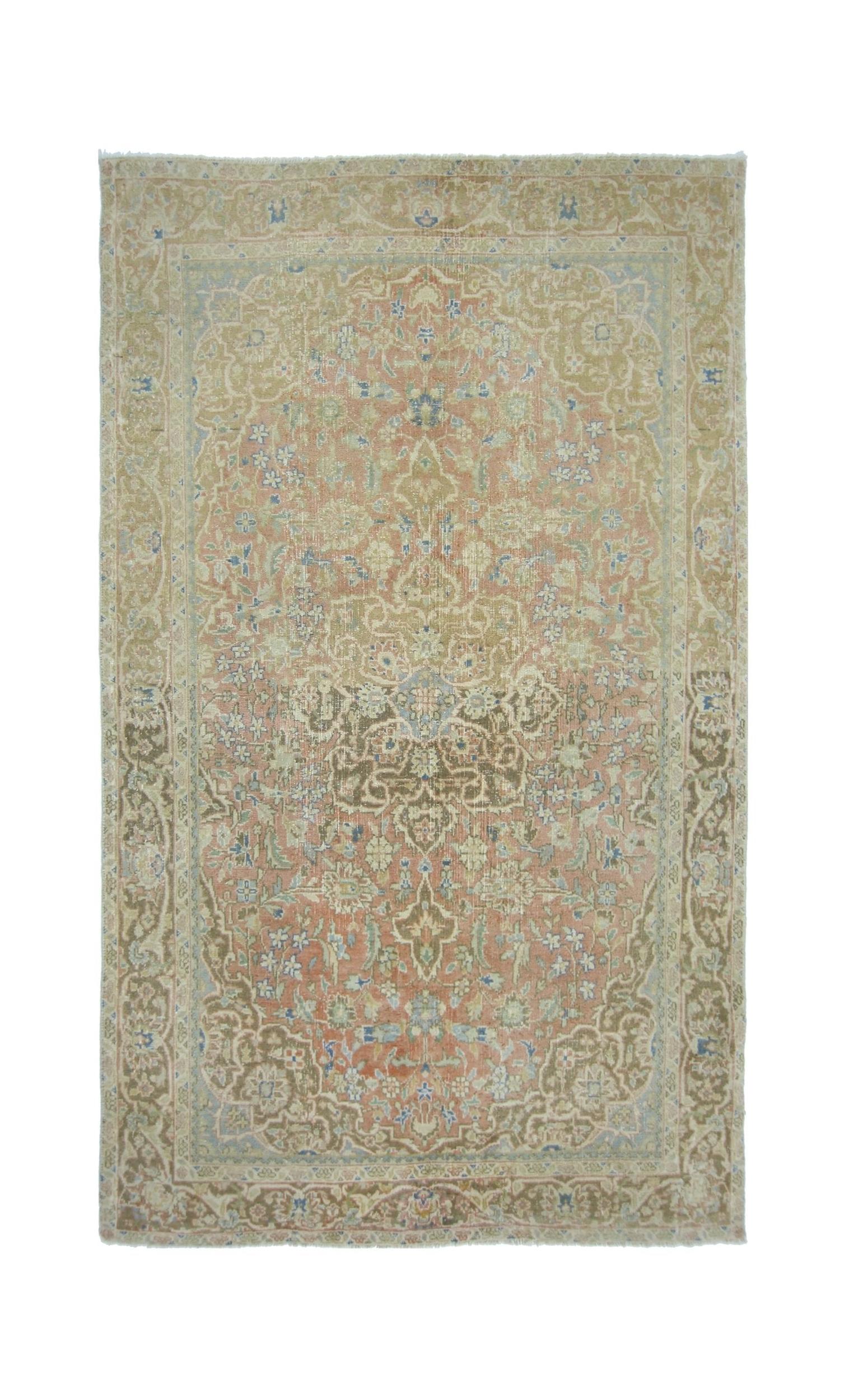 A vintage Persian rug featuring a faded floral medallion pattern in soft pink, beige, and blue.