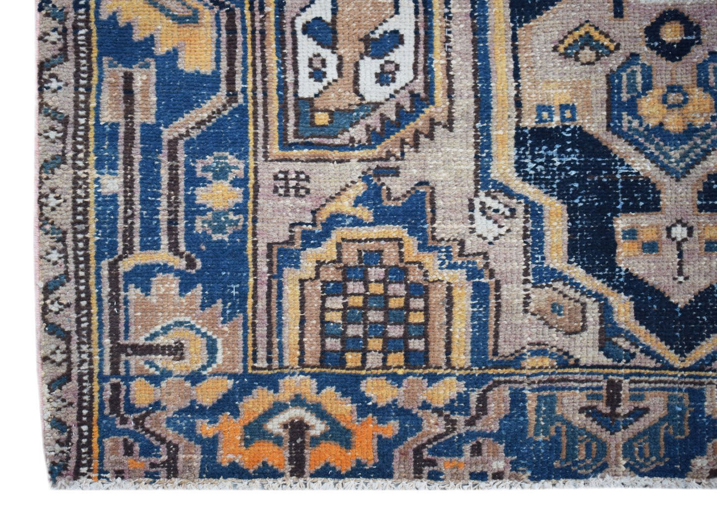 A handwoven vintage Persian rug featuring intricate geometric patterns in blue, tan, and orange.
