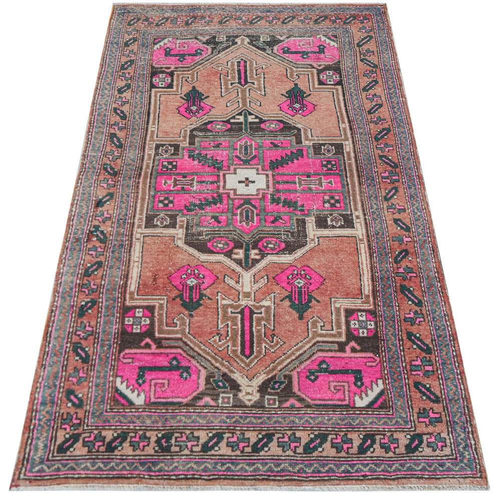 Vintage Persian rug with pink and brown geometric patterns.