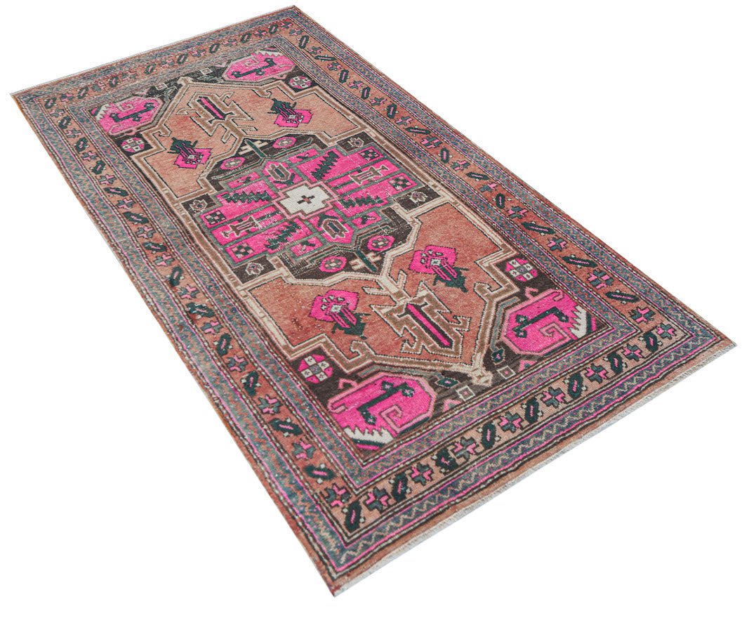 A handwoven vintage Persian rug featuring geometric patterns in shades of pink, brown, and cream.