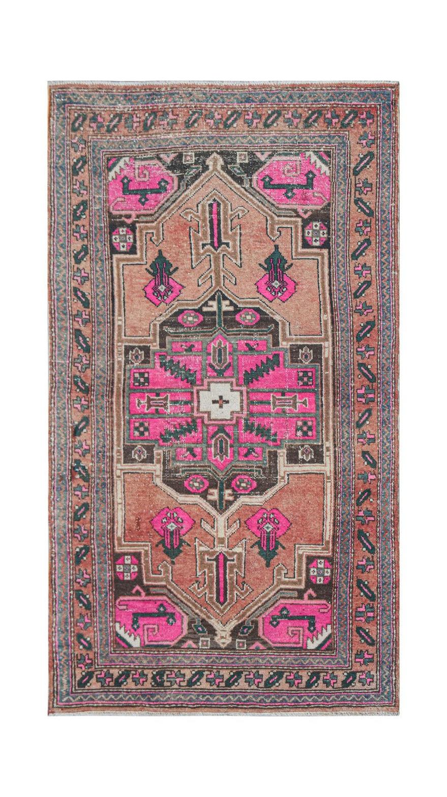 Vintage Persian rug with a central medallion and geometric patterns in pink and brown.