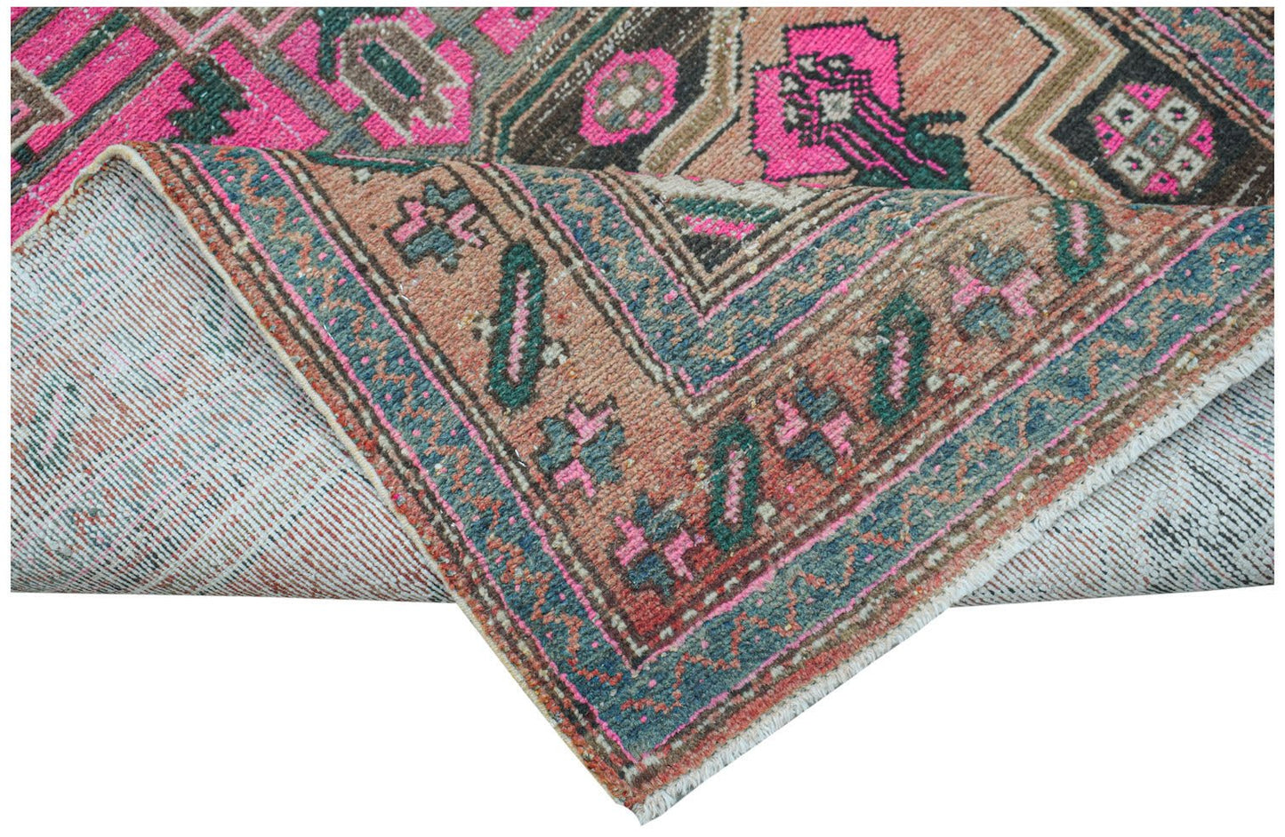 A vintage handwoven Persian rug featuring geometric patterns in vibrant pink, blue, and tan tones.