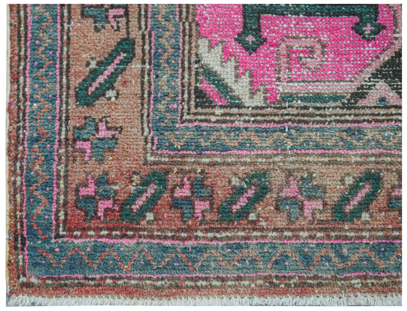 A vintage handwoven Persian rug featuring a distressed pink, green, and orange geometric pattern.