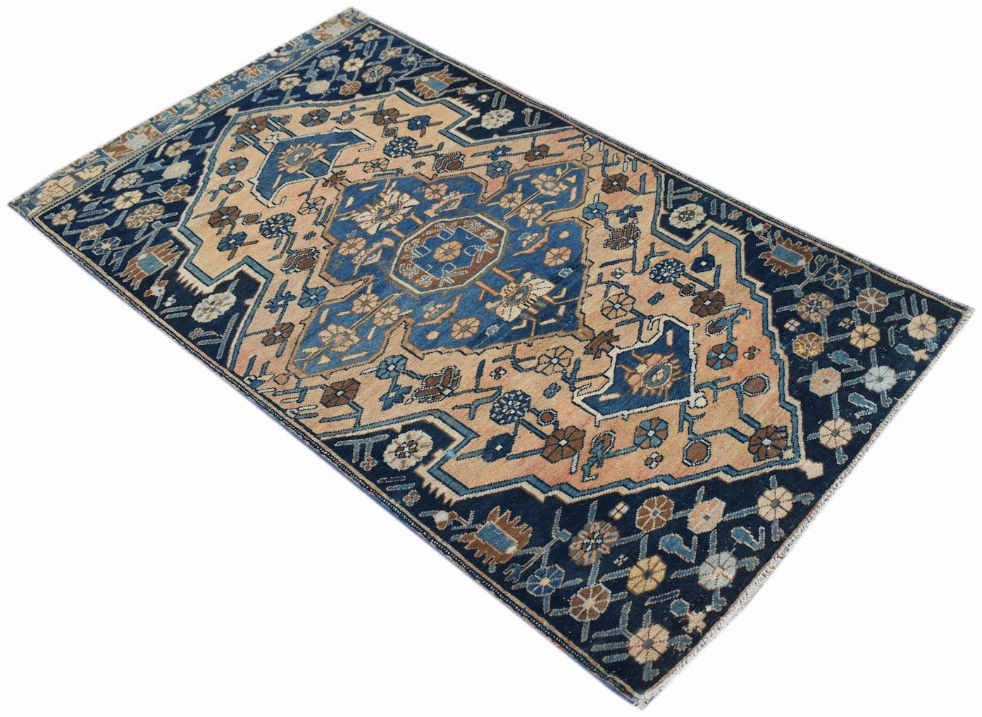 A handwoven vintage Persian rug featuring a geometric floral pattern in blue and tan tones.