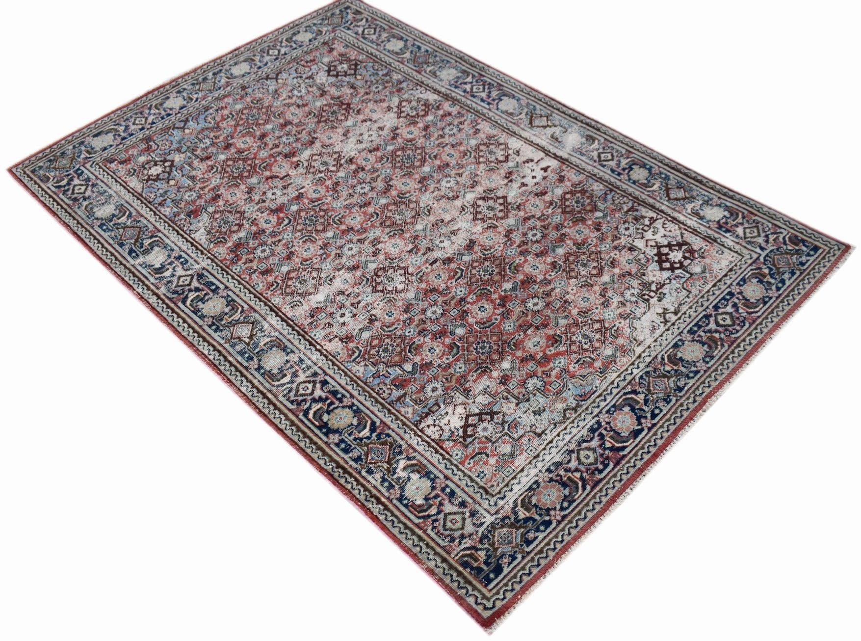 A rectangular vintage Persian rug featuring a faded red and blue geometric pattern.