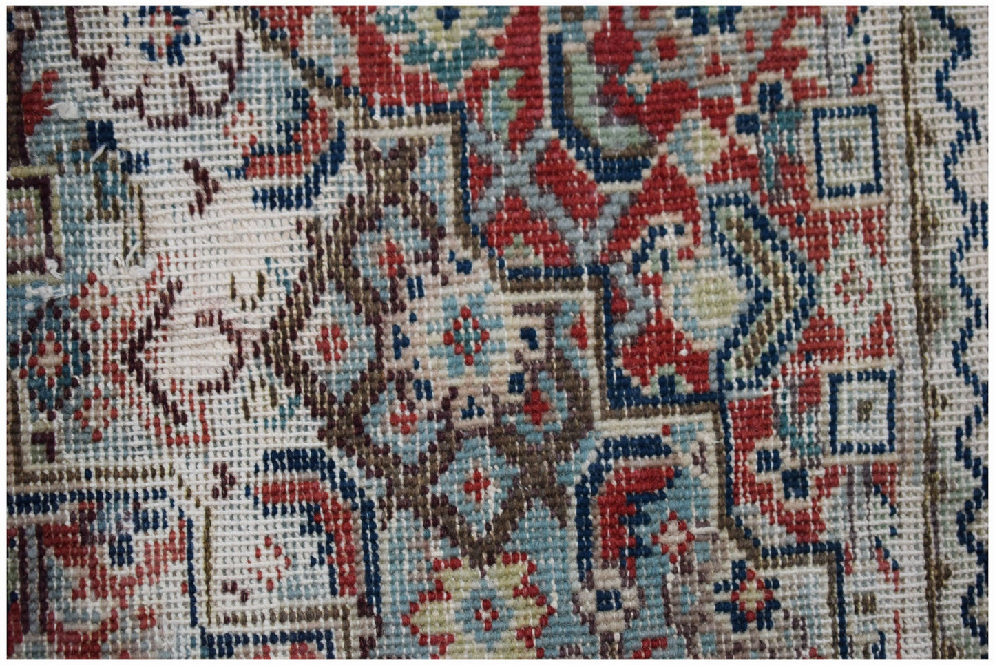 A handwoven vintage Persian rug featuring intricate geometric patterns in red, blue, and cream.