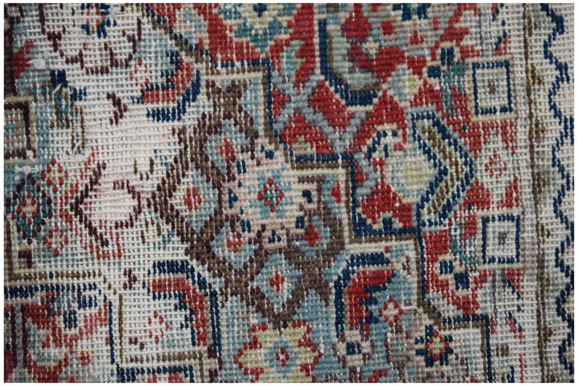 A handwoven vintage Persian rug featuring intricate geometric patterns in red, blue, and cream.