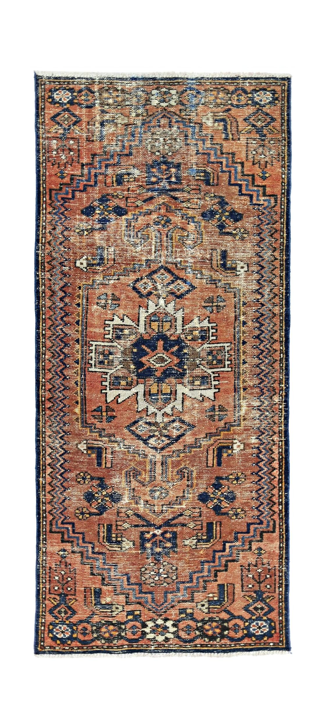 A vintage handmade Persian rug featuring a geometric medallion pattern in rust, blue, and cream.