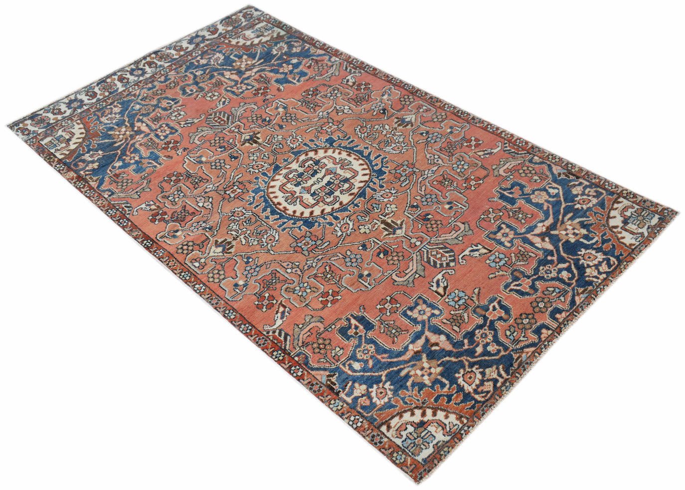 A vintage handwoven Persian rug featuring a floral pattern in shades of coral, blue, and cream.