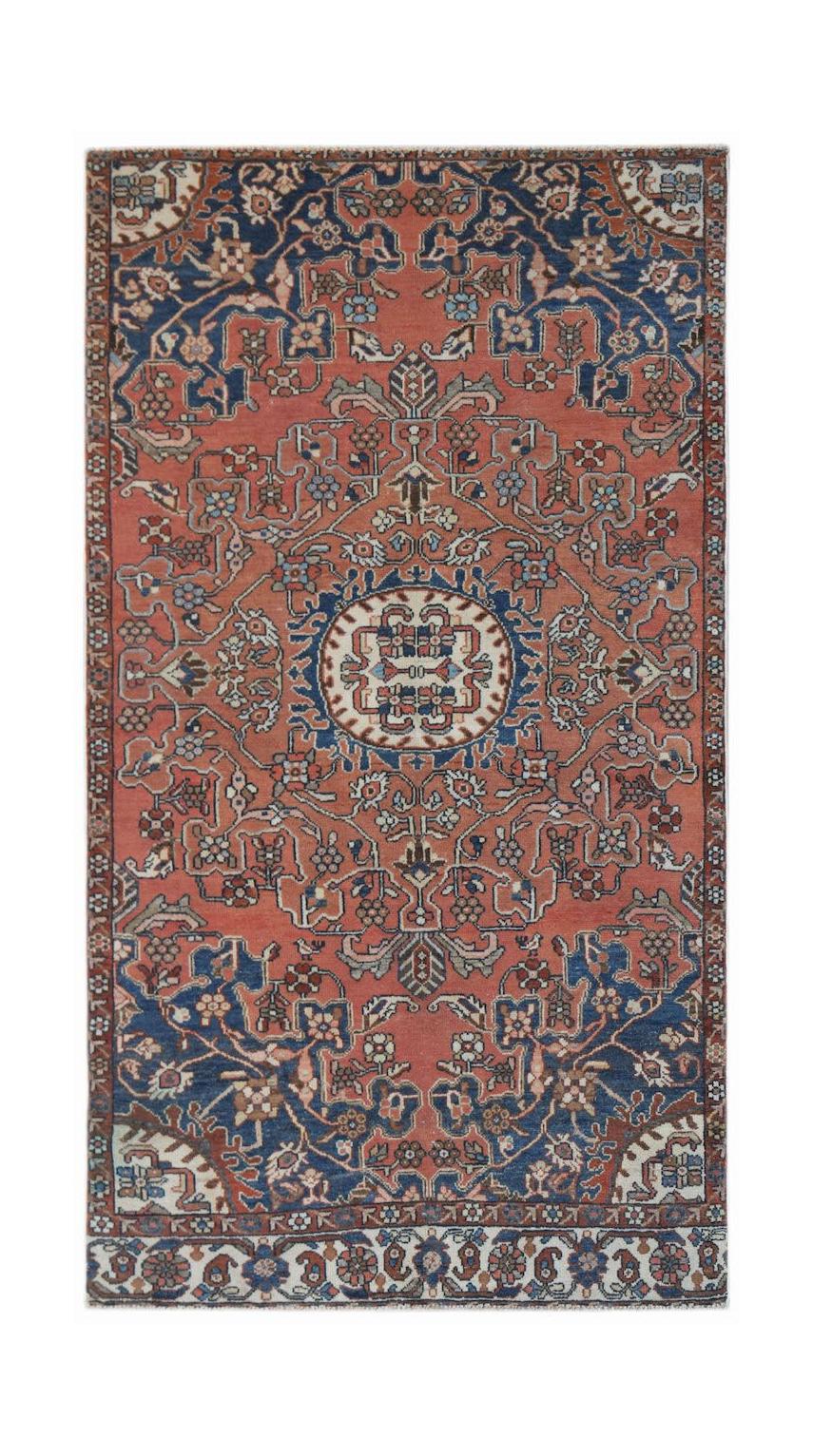 A handwoven vintage Persian rug featuring a central medallion on a terracotta and blue field.