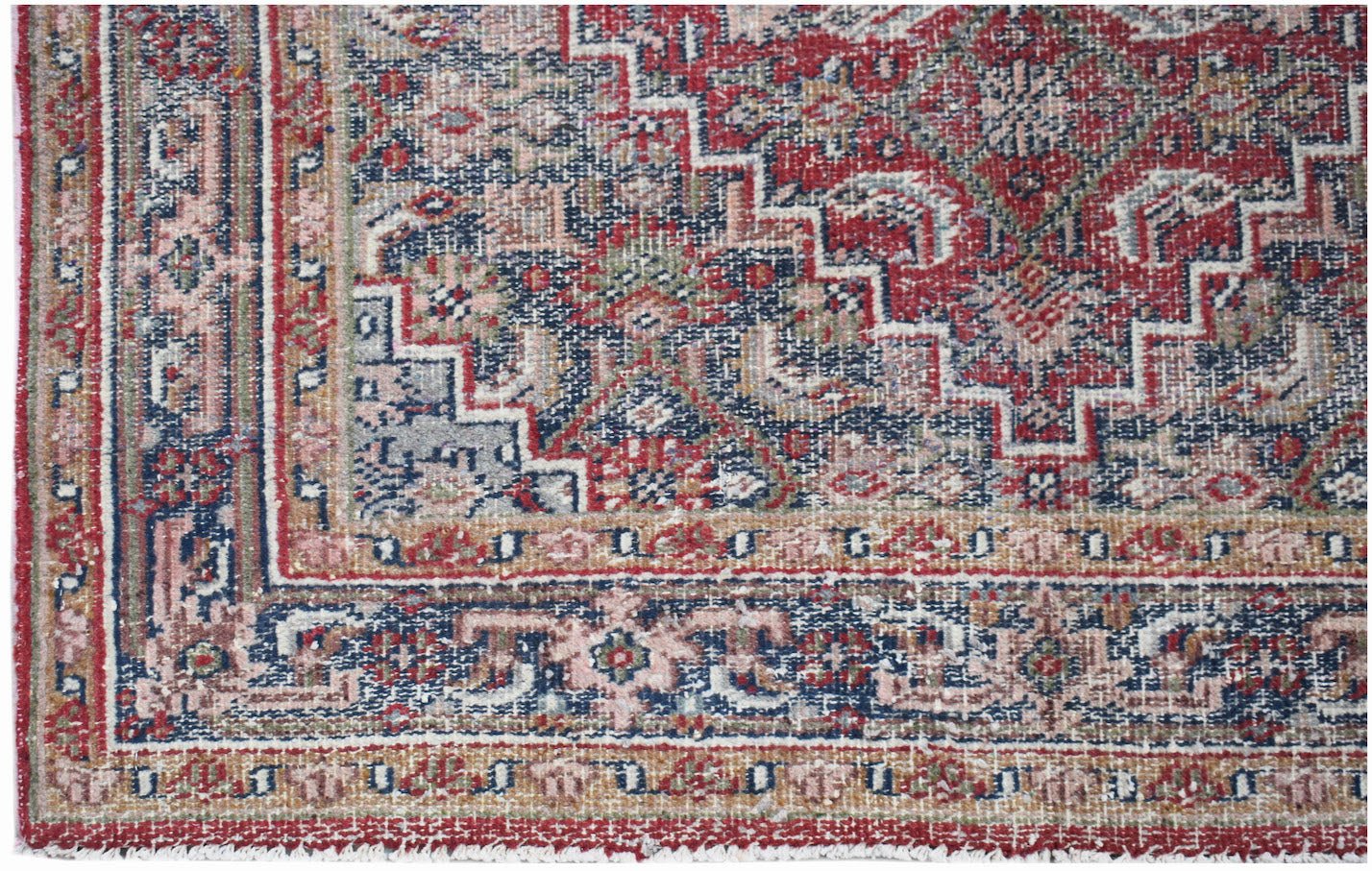 A vintage handwoven Persian rug featuring a distressed red and blue geometric pattern.