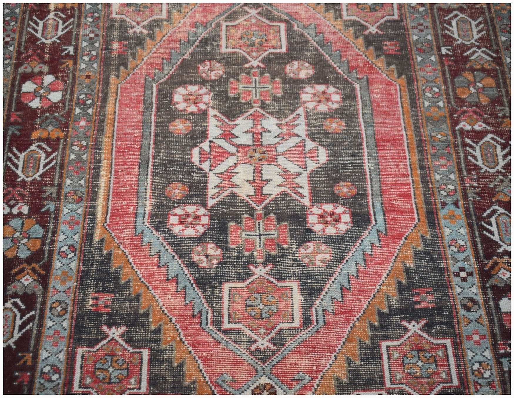 A vintage handwoven Persian Hamadan rug featuring a central geometric medallion in red and charcoal.