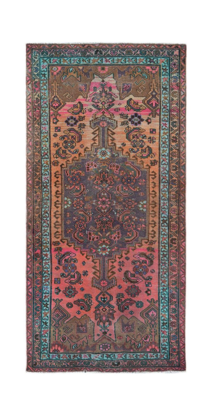 A handwoven vintage Persian rug featuring a central medallion with pink, orange, and purple tones.