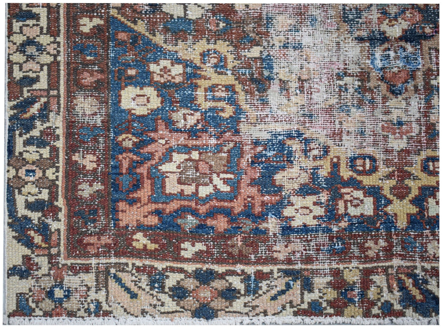A handwoven vintage Persian rug featuring a distressed floral pattern in blue, red, and beige.