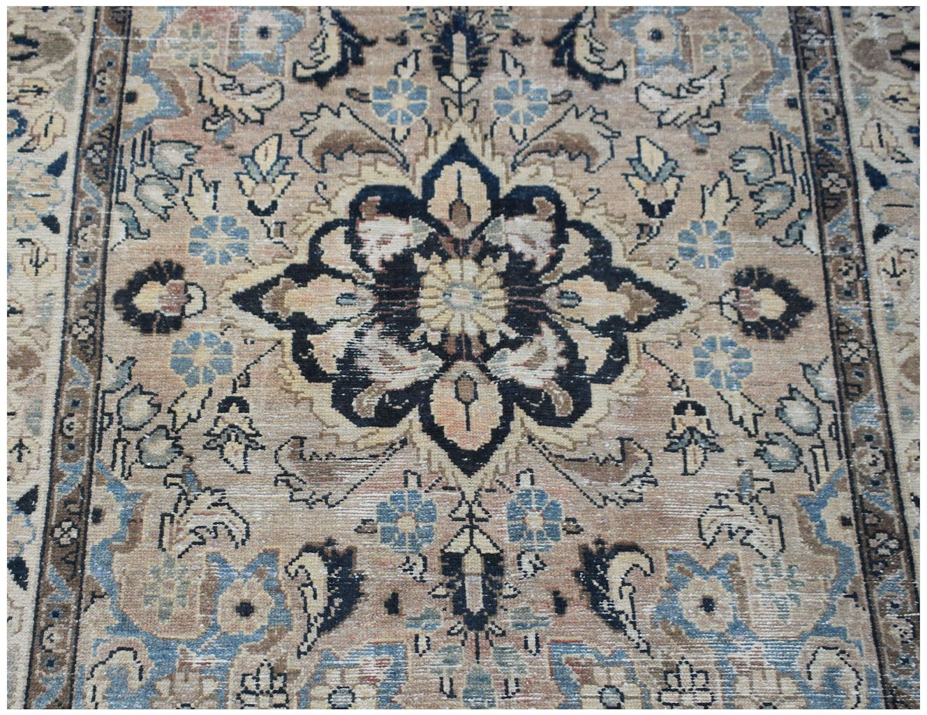 A vintage handwoven Persian Sarouk rug featuring a central floral medallion in muted earth tones.