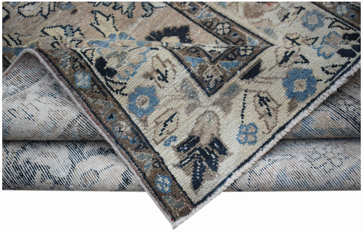 A vintage handwoven Persian Sarouk rug featuring a worn floral pattern in blue and beige tones.