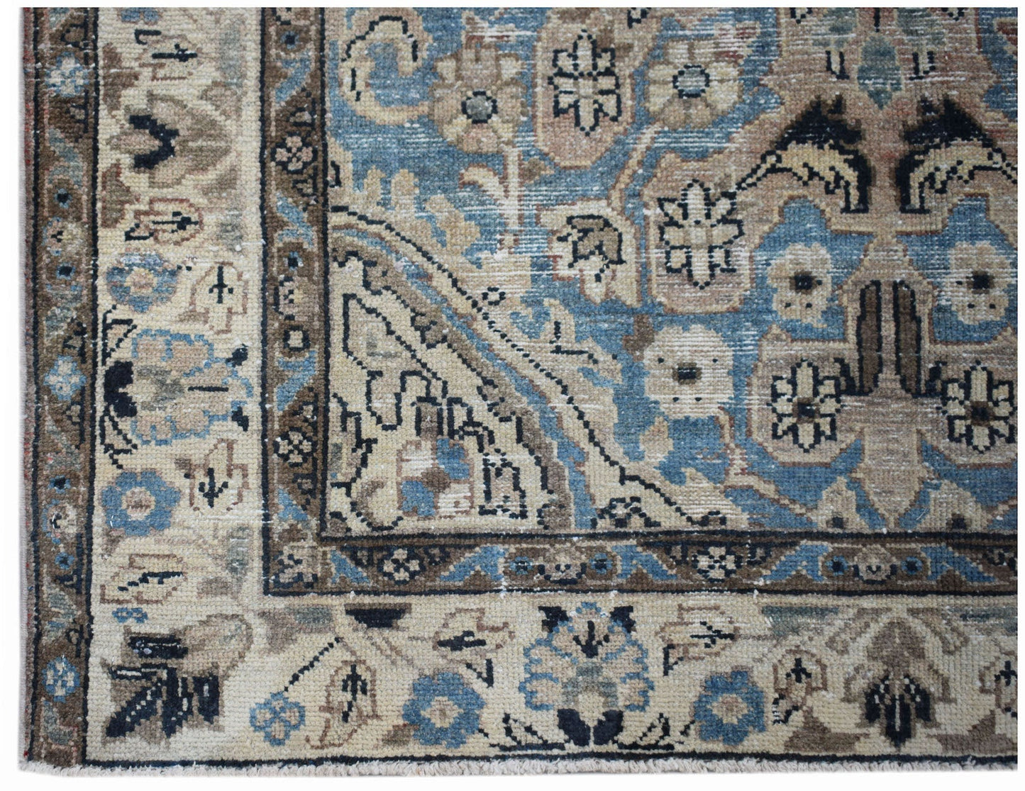 A vintage handwoven Persian Sarouk rug featuring intricate floral patterns in blue and beige.