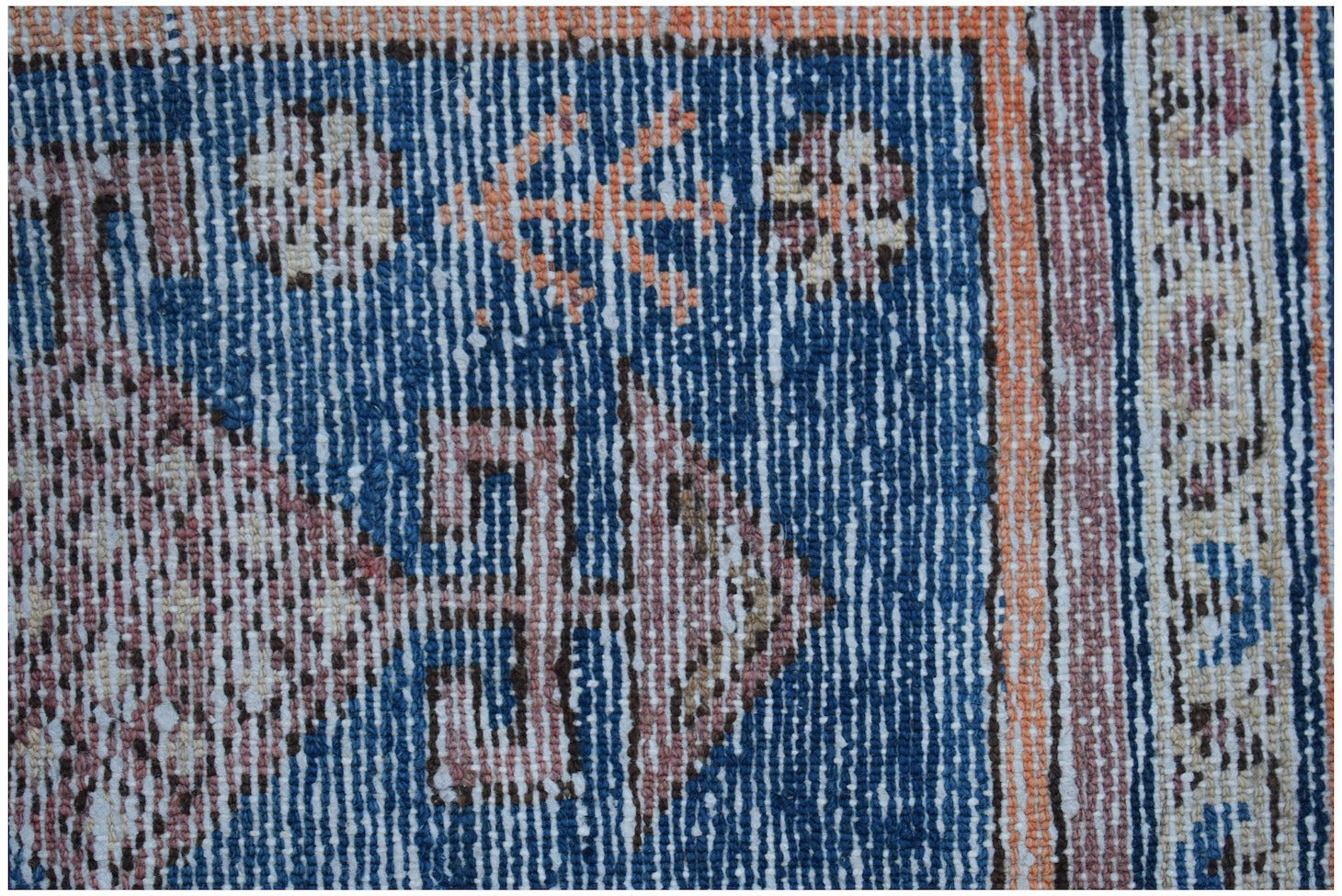 Close-up of a vintage Persian rug with blue, orange, and cream geometric patterns.