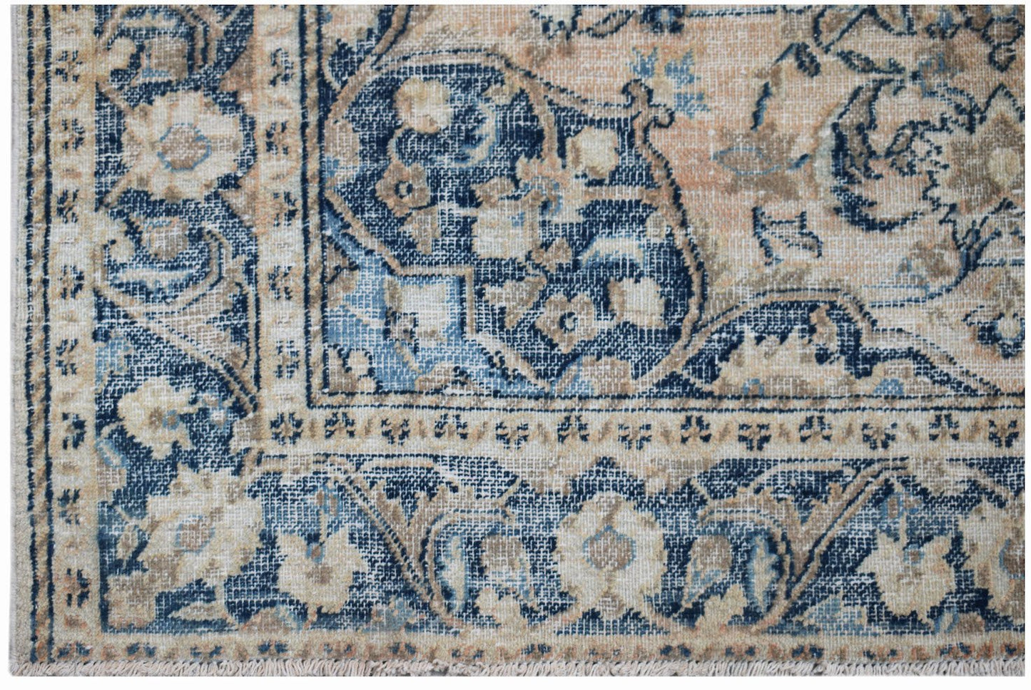 A vintage handwoven Persian rug featuring a faded floral pattern in shades of blue and beige.