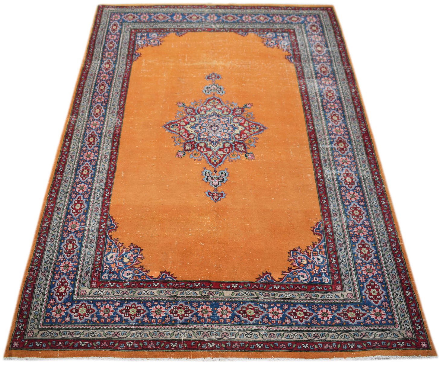 A vintage Persian Mashad rug featuring a central floral medallion on a bright orange field.