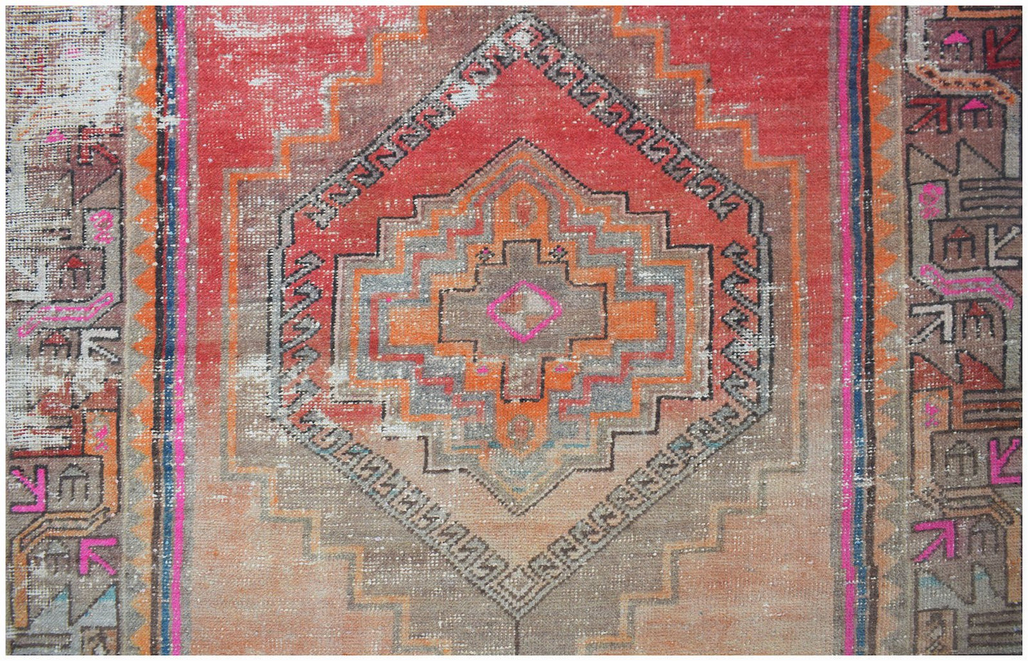 A vintage handwoven Persian rug featuring a geometric diamond medallion in red, orange, and grey.