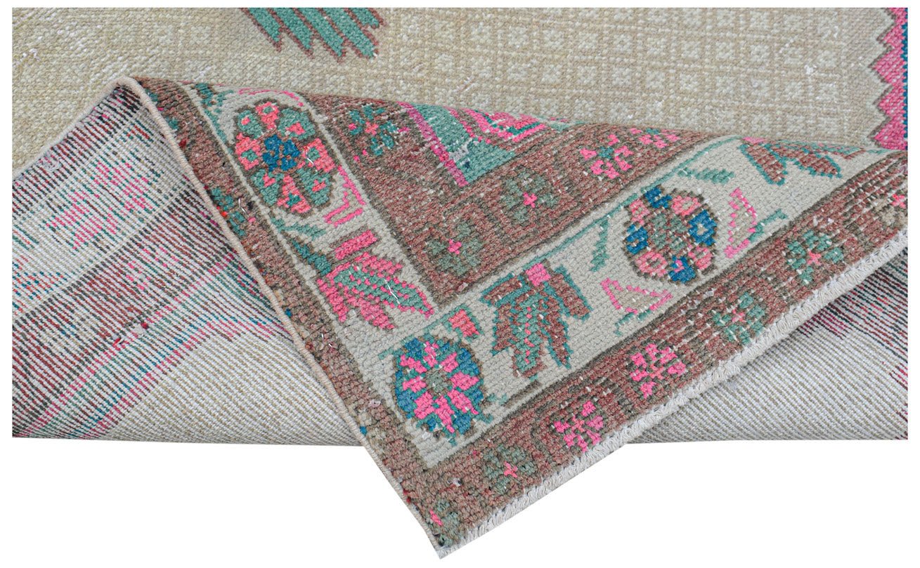 A vintage handwoven Persian rug featuring a floral pattern in pink, blue, and green on beige.