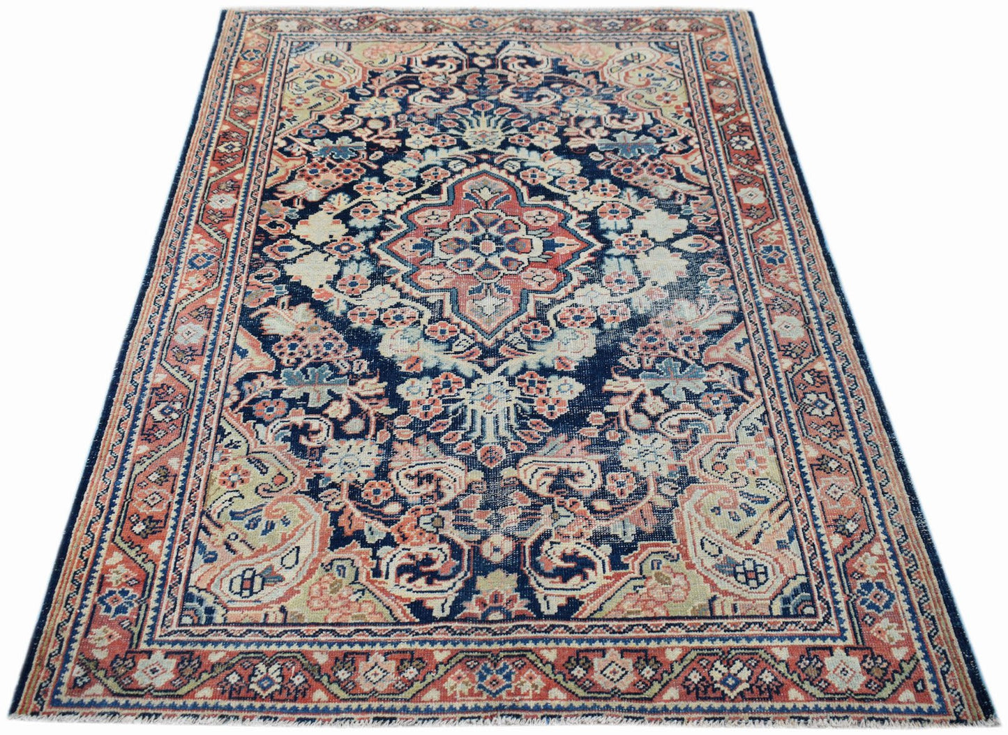 A vintage handwoven Persian rug featuring a central floral medallion on a dark blue field.