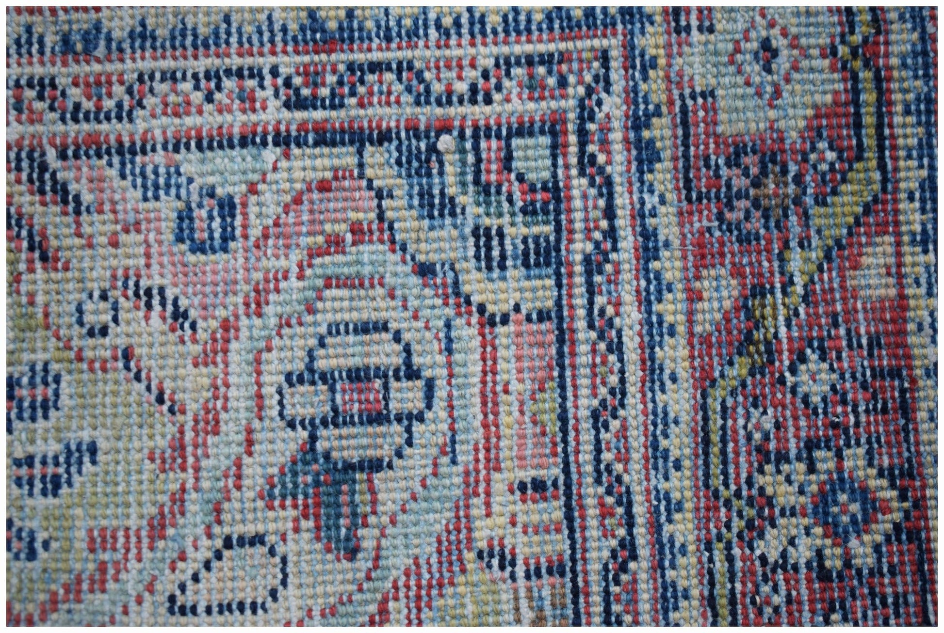 A close-up of a handwoven vintage Persian rug featuring intricate blue and red geometric patterns.