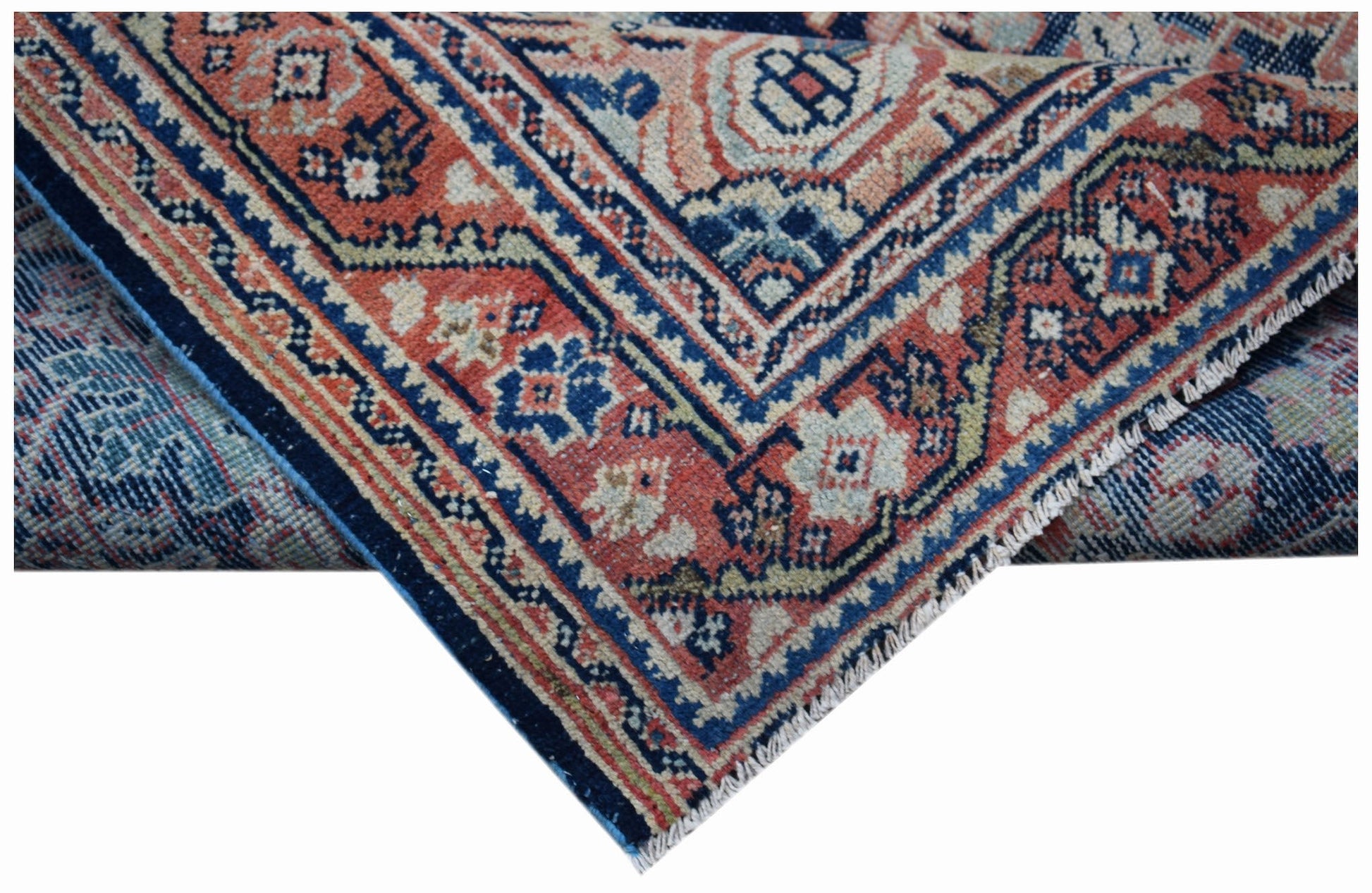A vintage handwoven Persian rug featuring intricate geometric patterns in red, blue, and cream.