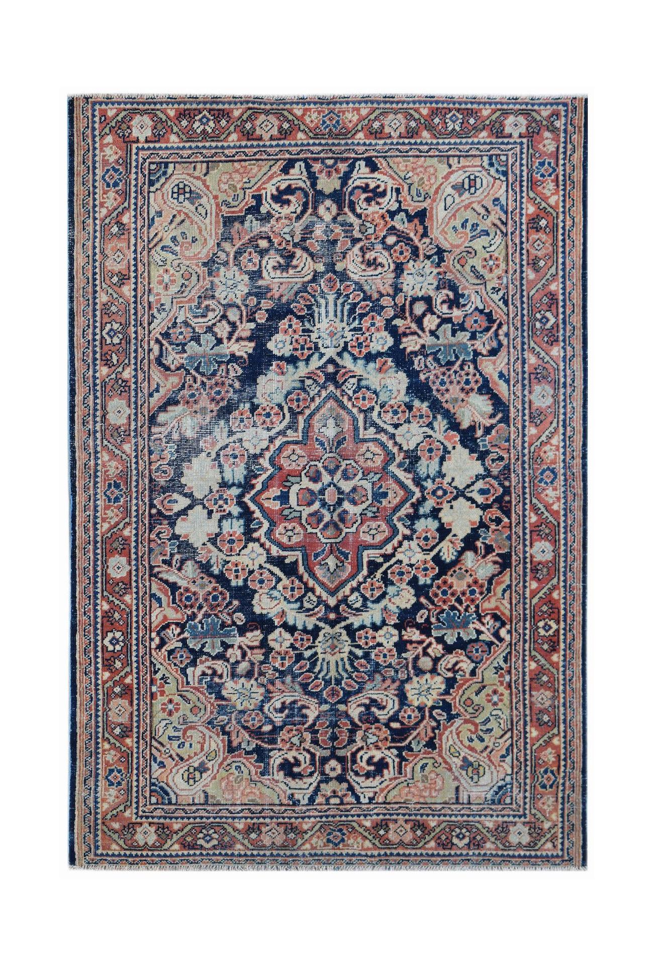 A vintage handwoven Persian rug featuring a central floral medallion on a dark blue field.