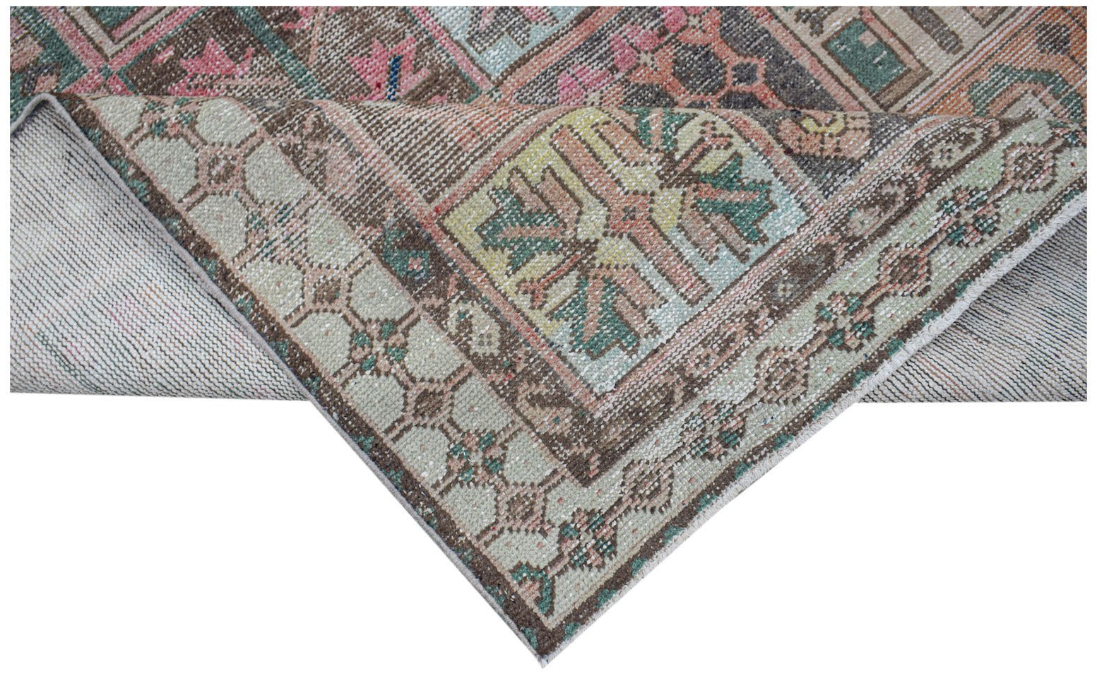 A vintage handwoven Persian rug featuring a faded geometric pattern in muted earth tones.