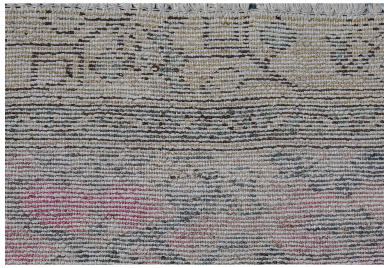 A close-up of a handwoven vintage Persian rug featuring a faded, distressed pattern in wool.