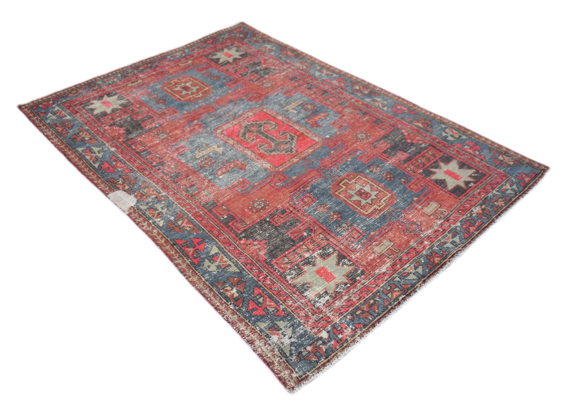 A vintage handwoven Persian rug featuring a distressed geometric pattern in red and blue tones.
