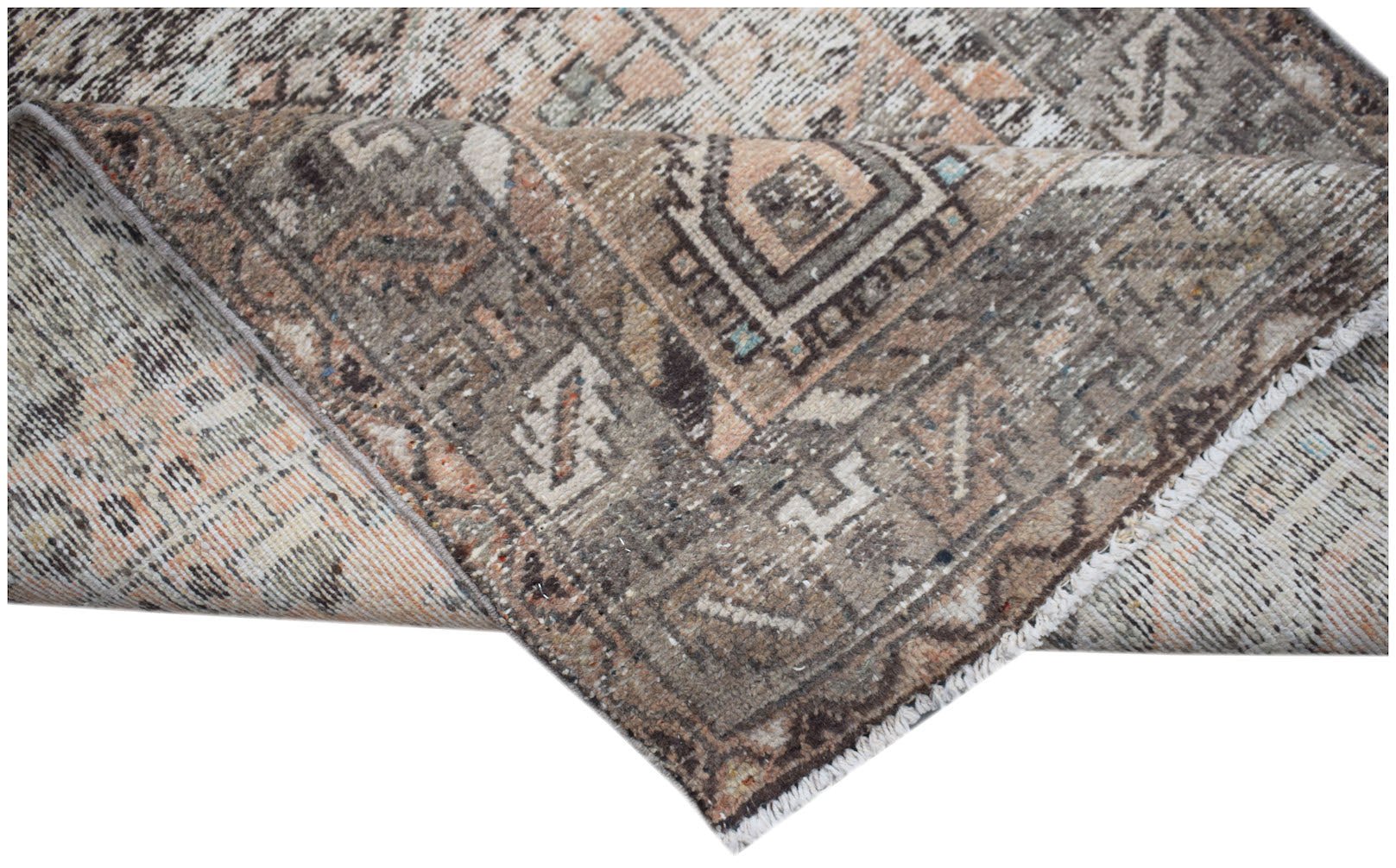 A handwoven vintage Persian rug featuring a faded geometric pattern in shades of brown and peach.