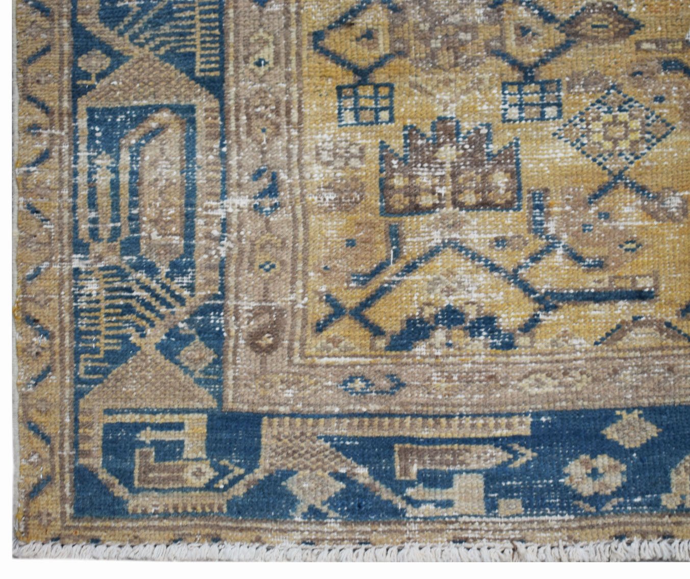A vintage handwoven Persian rug featuring a distressed geometric pattern in blue and gold tones.